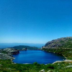 Scenic view of sea and mountains against clear blue sky