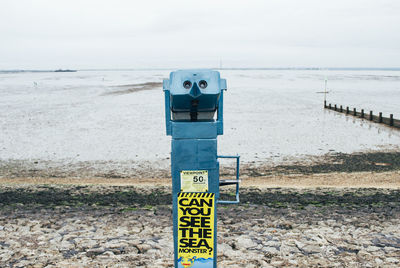 Information sign on beach against sky