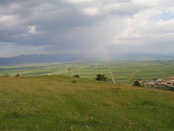 Scenic view of grassy field against cloudy sky