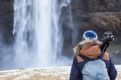 Photographer standing on cliff by waterfall