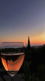 Close-up of beer glass against sunset