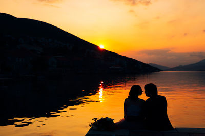 Silhouette couple against orange sky during sunset