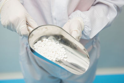 Midsection of person holding pills in measuring spoon