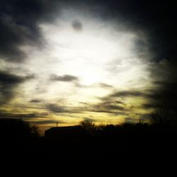 Silhouette of trees against cloudy sky