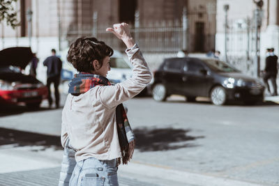 Side view of woman hitchhiking on street