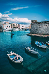 Boats moored in sea against buildings in city