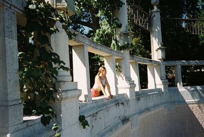 Woman sitting by building