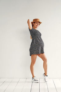 Portrait of young woman standing against wall