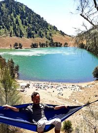 Portrait of man sitting on shore by lake