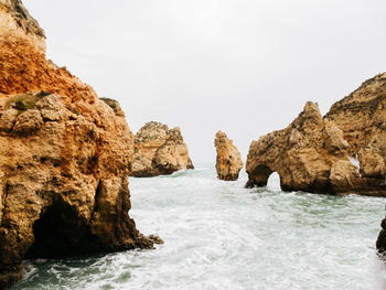 Rock formations in sea against clear sky