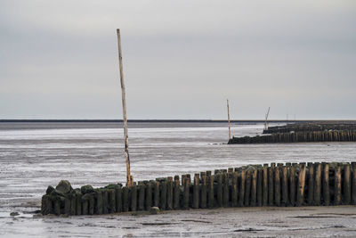 Wooden posts on beach against sky