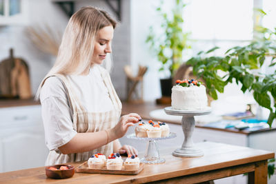 Smiling woman preparing cupcakes at home