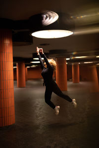 Woman jumping in illuminated garage