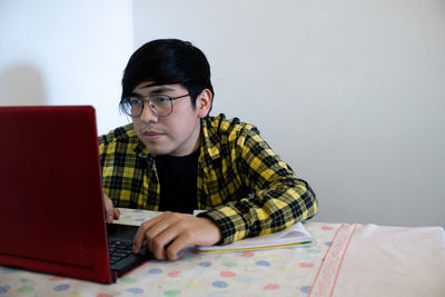 Young man using mobile phone while sitting on table