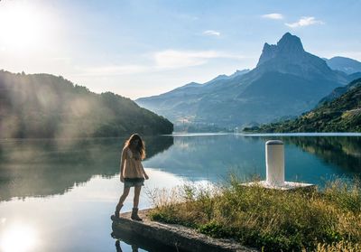 Mature woman standing by calm lake against sky