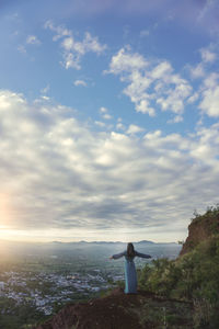 Rear view of woman standing on landscape against sky