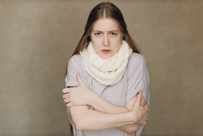 Portrait of young woman standing against wall
