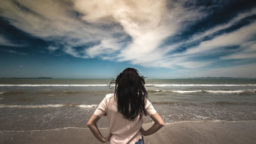 Rear view of woman at beach against sky