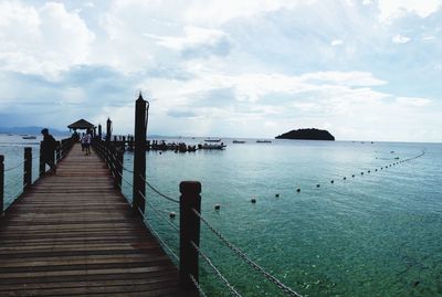 Pier on sea against cloudy sky