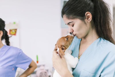 Close-up of doctor embracing with puppy at hospital