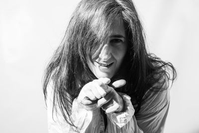 Portrait of young woman holding face against white background