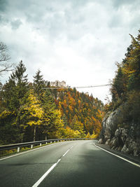 Road amidst trees against sky during autumn