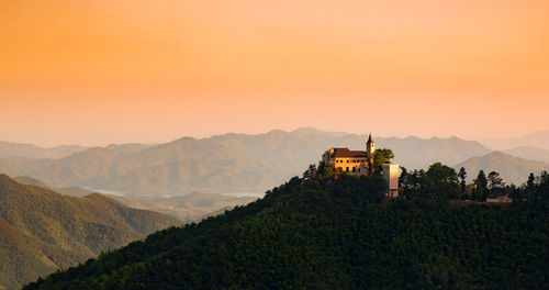 Panoramic view of building and mountains against sky during sunset