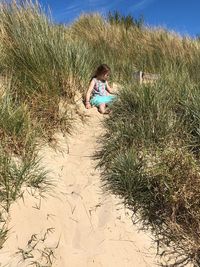Full length of woman sitting on grass at beach