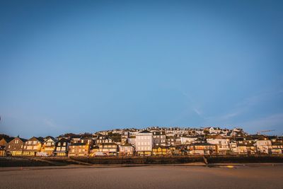 Illuminated cityscape against clear blue sky