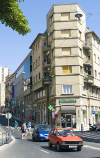 Cars on road by buildings in city against clear sky