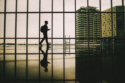 Silhouette man walking by window in corridor