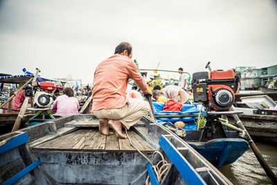 Rear view of people on boats moored at harbor