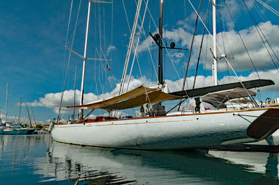 Sailboats moored in harbor against sky