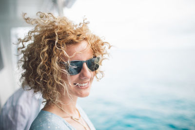 Smiling woman wearing sunglasses against sea