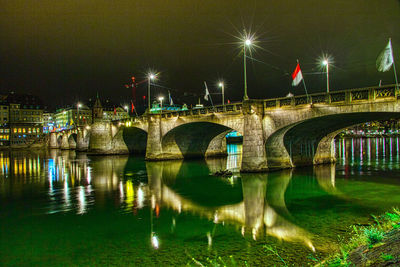 Illuminated bridge over river against sky at night