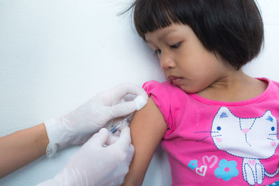 Cropped hands of doctor injecting girl at hospital