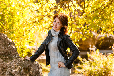 Happy young woman in park on sunny autumn day. cheerful beautiful girl in gray