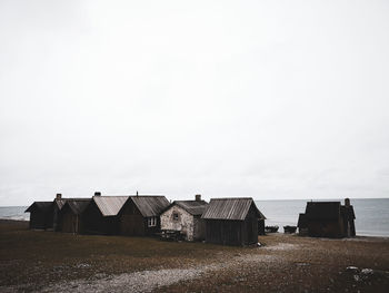 Houses by sea against clear sky