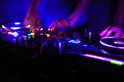 Cropped image of people playing illuminated dj in club