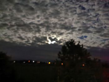 Defocused image of silhouette trees against sky at night