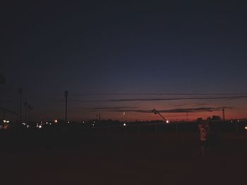 Silhouette illuminated lights against clear sky at night