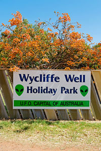 Information sign on field against trees during autumn