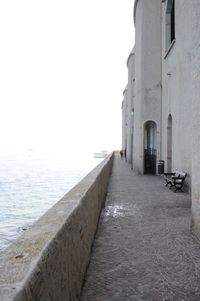 Footpath amidst buildings against clear sky