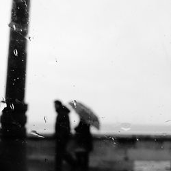 Close-up of wet window against sky