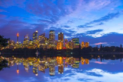 Reflection of illuminated cityscape against sky at night