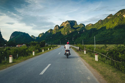 Man riding motorcycle on road against sky