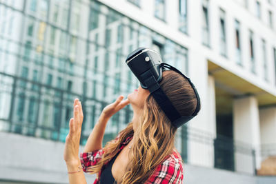 Woman standing outdoors wearing virtual reality headset