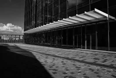 Empty footpath amidst buildings in city against sky