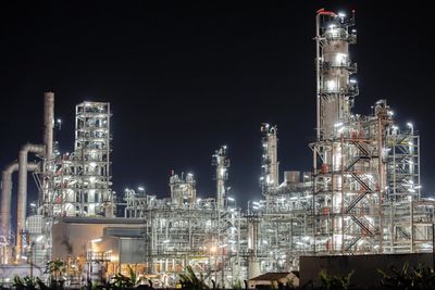 Illuminated factory against sky at night