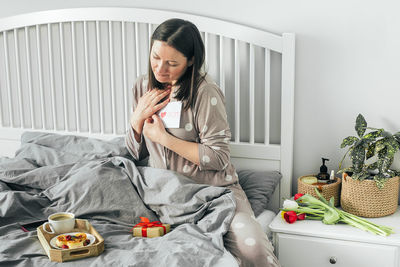 Young woman sitting on bed at home